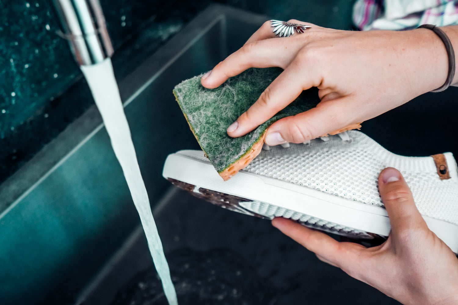 Une dame en train de nettoyer ses chaussures blanches SAOLA avec une éponge et du savon